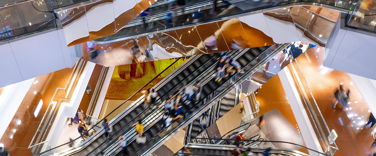 Bird's eye view of people on escalators inside a shopping centre