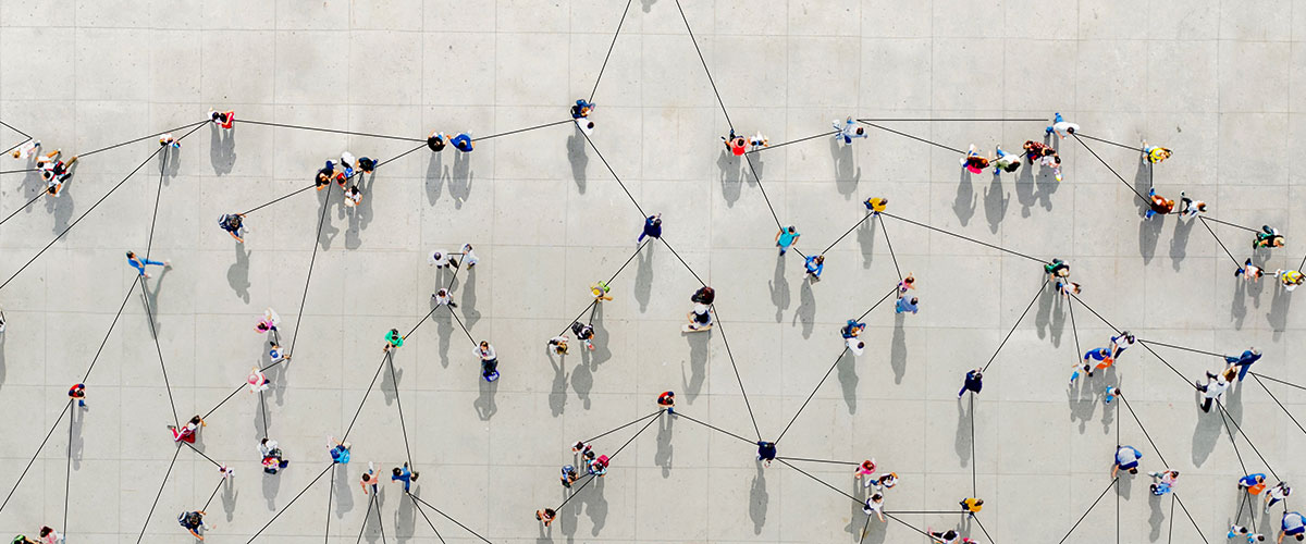 Bird's eye view of people joined by lines on a concrete surface to represent networking connections